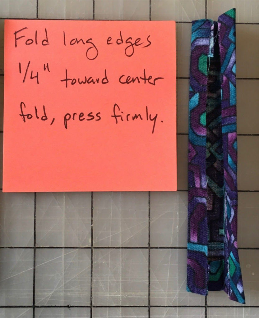 Fold long edges 1/4" toward center fold, press firmly.